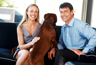 Happy young couple sitting with their pet dog at home