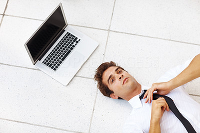 Businessman lying on floor with a laptop fixing his tie