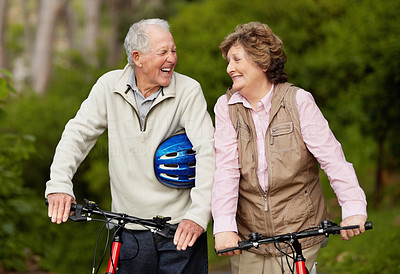 Cheerful matured couple with bicycle in countryside