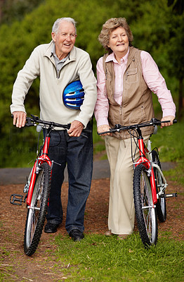 Cheerful matured couple with bicycle in countryside