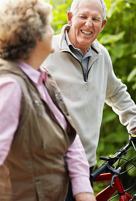 Happy mature man with senior woman riding bicycle in countryside