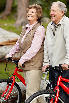Sporty mature couple walking with bicycle in countryside