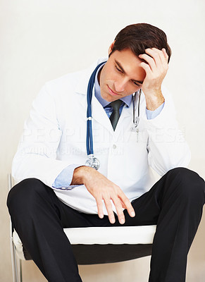 Overworked doctor with hand on head , looking stressed out