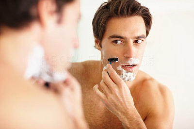Young guy shaving in the bathroom with a razor