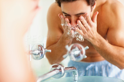 Young man at the bathroom basin washing his face