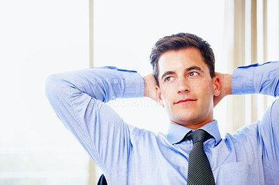 Relaxed thoughtful business man with hands behind head at work