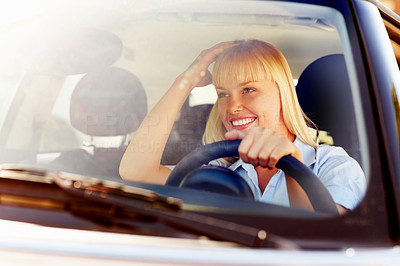 Woman adjusting hair while looking at rear view mirror of a car
