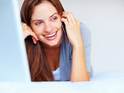 Happy young female speaking over cellphone on the bed