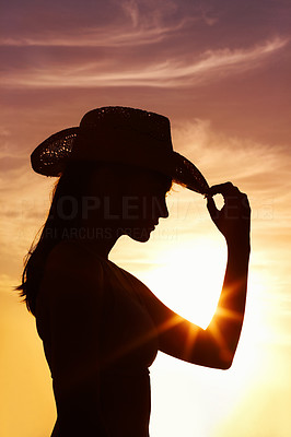 Profile view of a woman wearing a straw hat against sunset