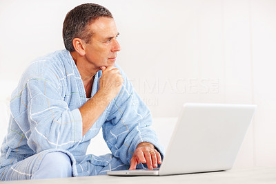 Retired man in bathrobe with laptop looking at copyspace