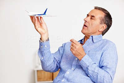 An elderly man playing with toy plane as he plans for vacation