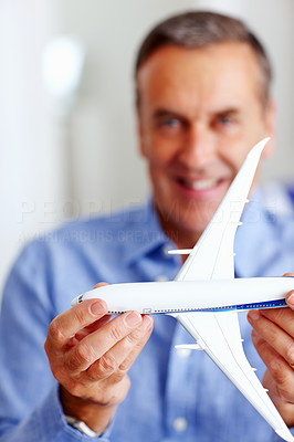 Happy senior man holding toy plane in front of you