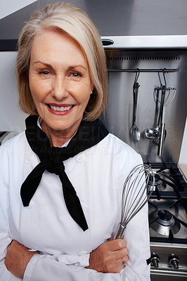 Female chef holding wire whisk standing in front of gas stove