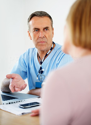 Senior doctor with laptop on desk consulting female patient