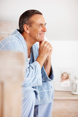 Happy mature man in bathrobe with hands on chin looking away