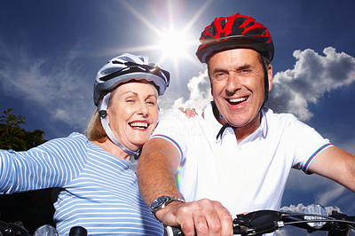 Senior couple with bicycles and protective helmet on a sunny day