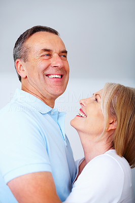 Senior couple hugging each other against blank background