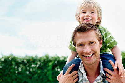 Smiling father carrying his son on shoulder with copyspace
