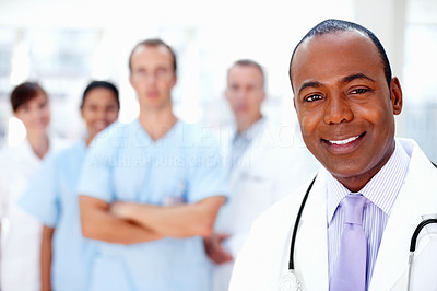 Confident doctor with medical team in background