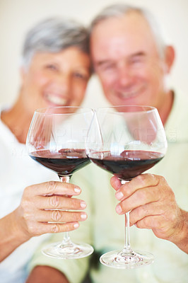 Smiling mature couple toasting with red wine