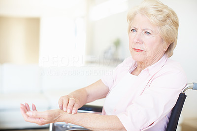 Elderly woman in a wheelchair checking her pulse at the wrist