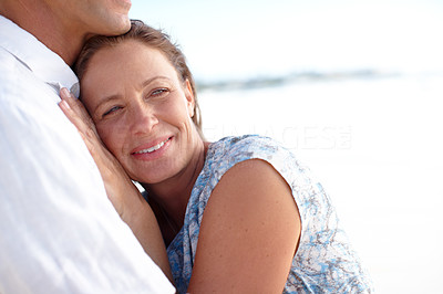 A mature man embracing his happy wife from behind as they stand on the beach