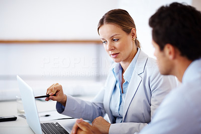 Business woman showing something to colleague on laptop
