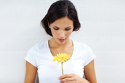 Goregous young lady holding a yellow flower on white