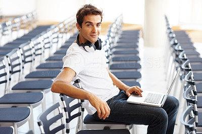 Young man sitting alone in auditorium with a laptop