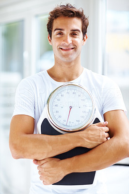 Healthy young man holding a weight scale
