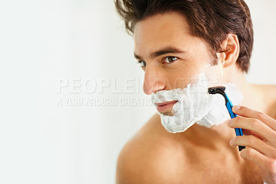 Closeup of a young smart man shaving using a razor