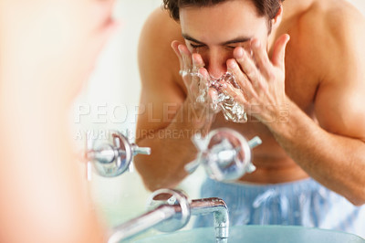 Young man at the bathroom basin washing his face