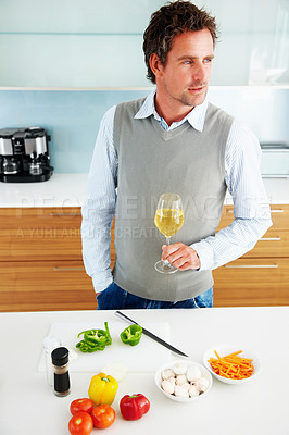 Mature man with wine standing in kitchen