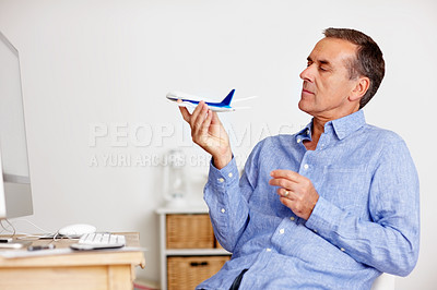 Senior man looking at toy plane as he plans for vacation