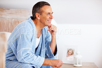 Smiling mature man in bathrobe with hand on chin - copyspace