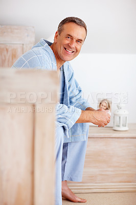 Smiling mature man in bathrobe sitting on bed