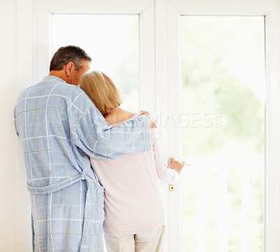 Romantic mature couple looking through glass door