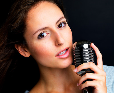 Lovely young female jazz singer singing into a retro microphone