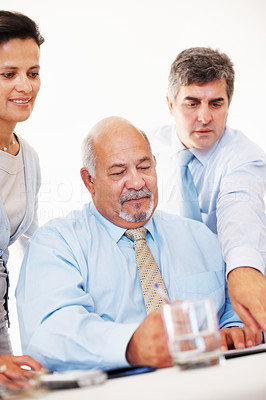 Mature male executive pointing at document to senior colleagues