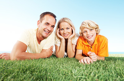 Cheerful family lying on meadow against sky