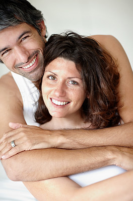 Mature man embraces woman from back smiling