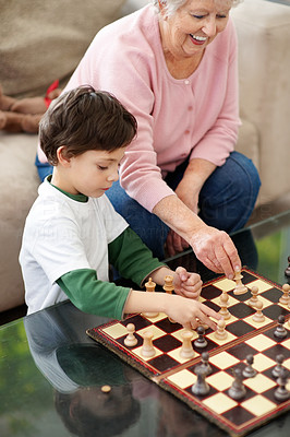 Adorable boy playing chess with his grandmother