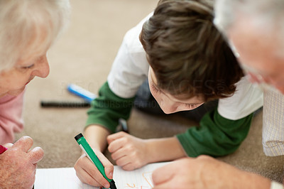 Adorable little boy making a drawing with his grandparents