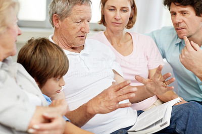 Senior man reading a book while sitting with his family