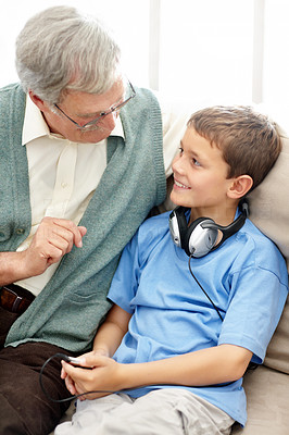 Old man sitting with his grandson wearing a headphone