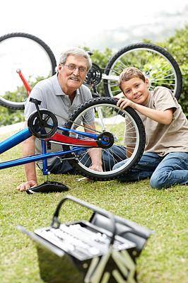 Little boy fixing a bicycle tyre with his grandfather