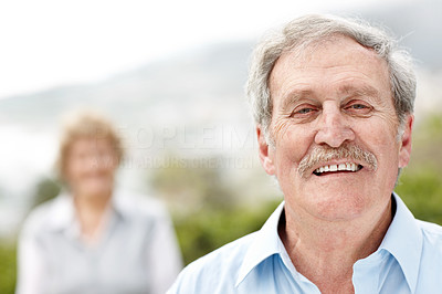 Smiling old man with a woman in bakcground
