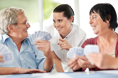 Smiling mature woman with old people playing cards