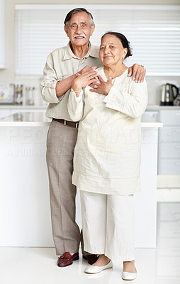 Happy old couple standing together in a kitchen