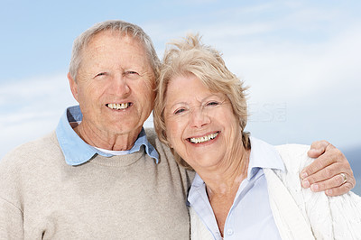 Happy old couple smiling together against the sky